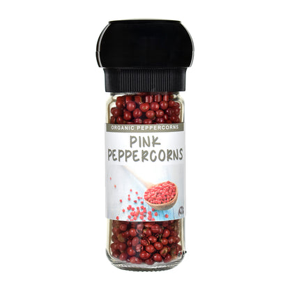 Jar of pink peppercorns with a black  grinder lid on a white background