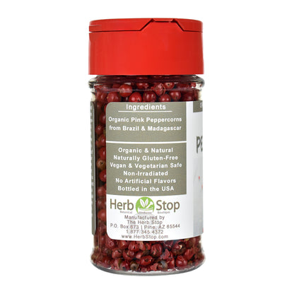 Jar of organic pink peppercorns with a red lid on a white background