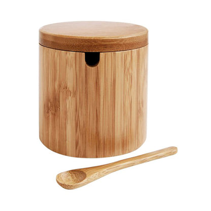 Wooden salt storage jar with a lid and a wooden spoon on a white background