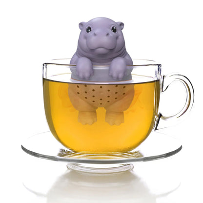 Hippo-shaped tea infuser in a glass of tea on a white background