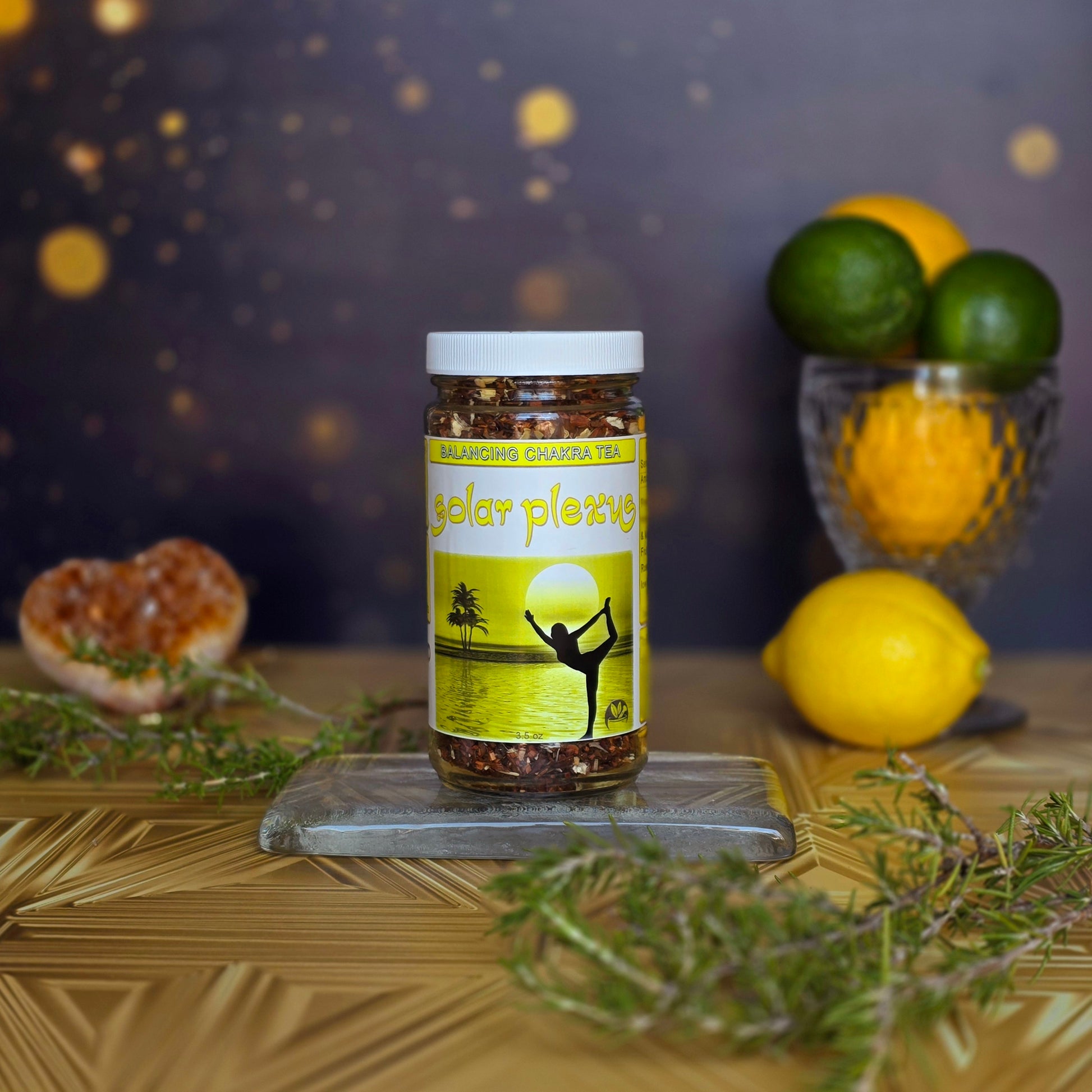 Solar Plexus Chakra Tea surrounded by rosemary and fresh citrus on a gold background