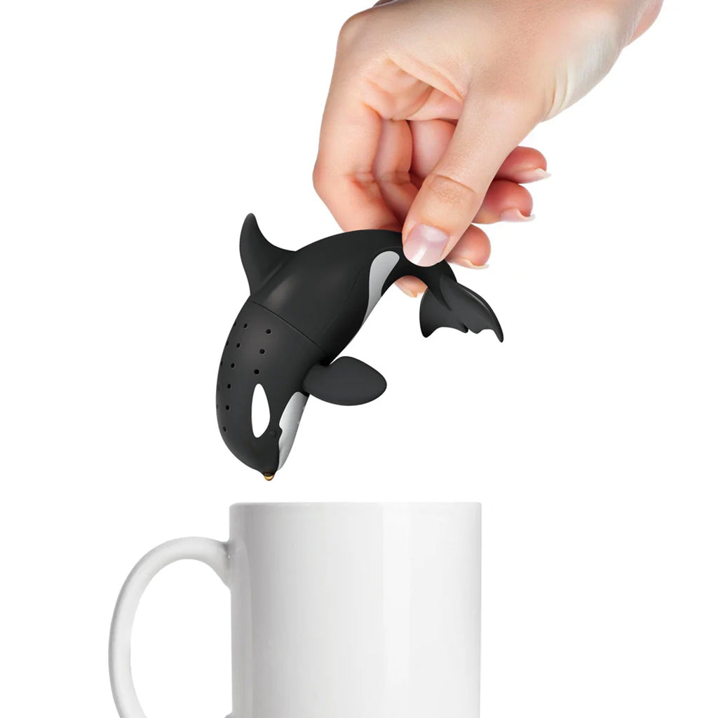 Orca whale-shaped tea infuser being held over a white mug