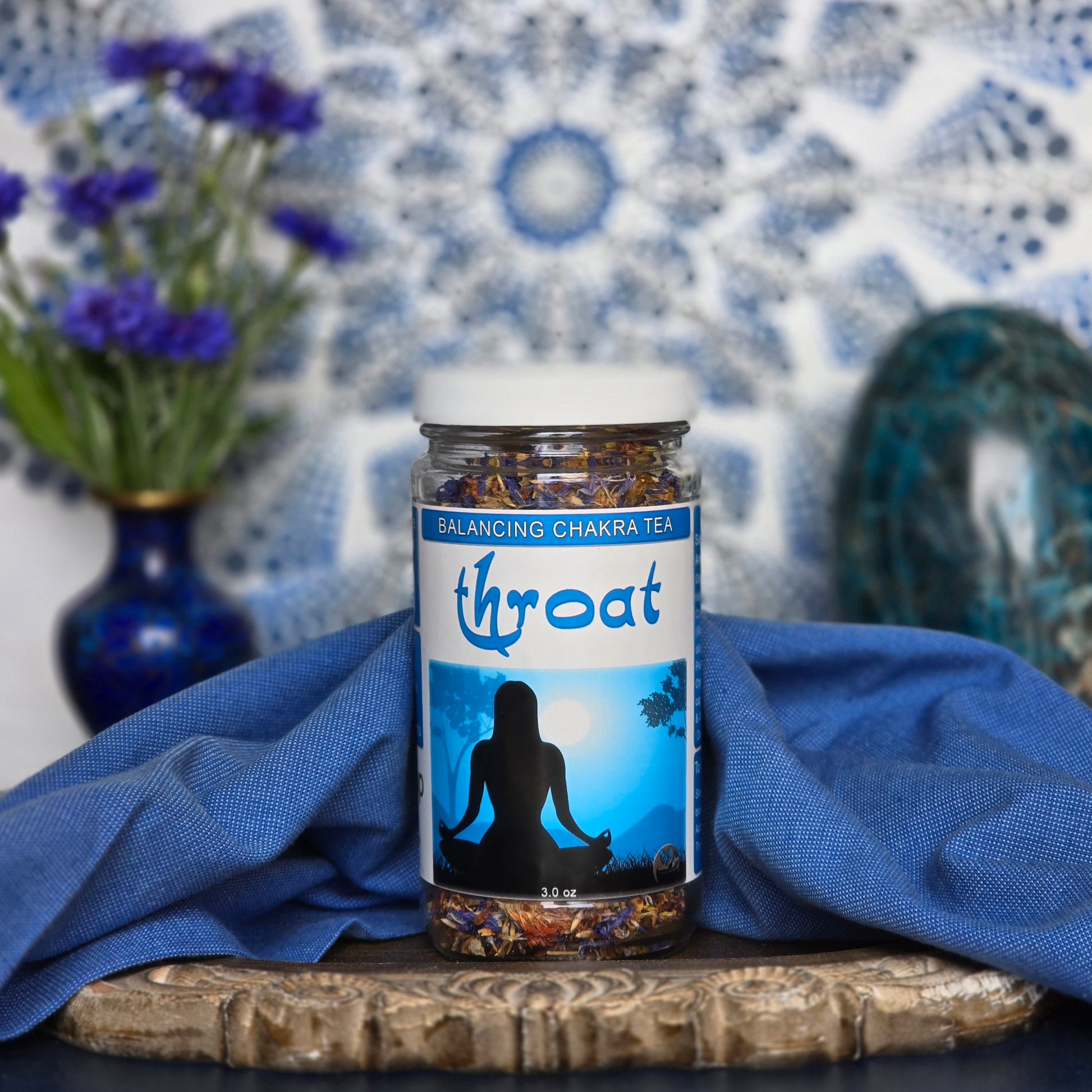 Glass Jar of Throat Chakra Tea with a mandala, flowers and crystal