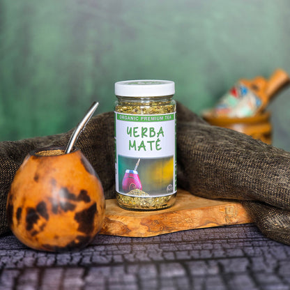Jar of Yerba Mate tea on a wooden board with a gourd and cloth in the background.