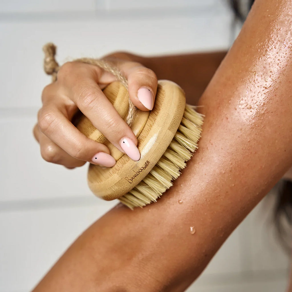 Person using a bamboo brush on their arm with a blurred background
