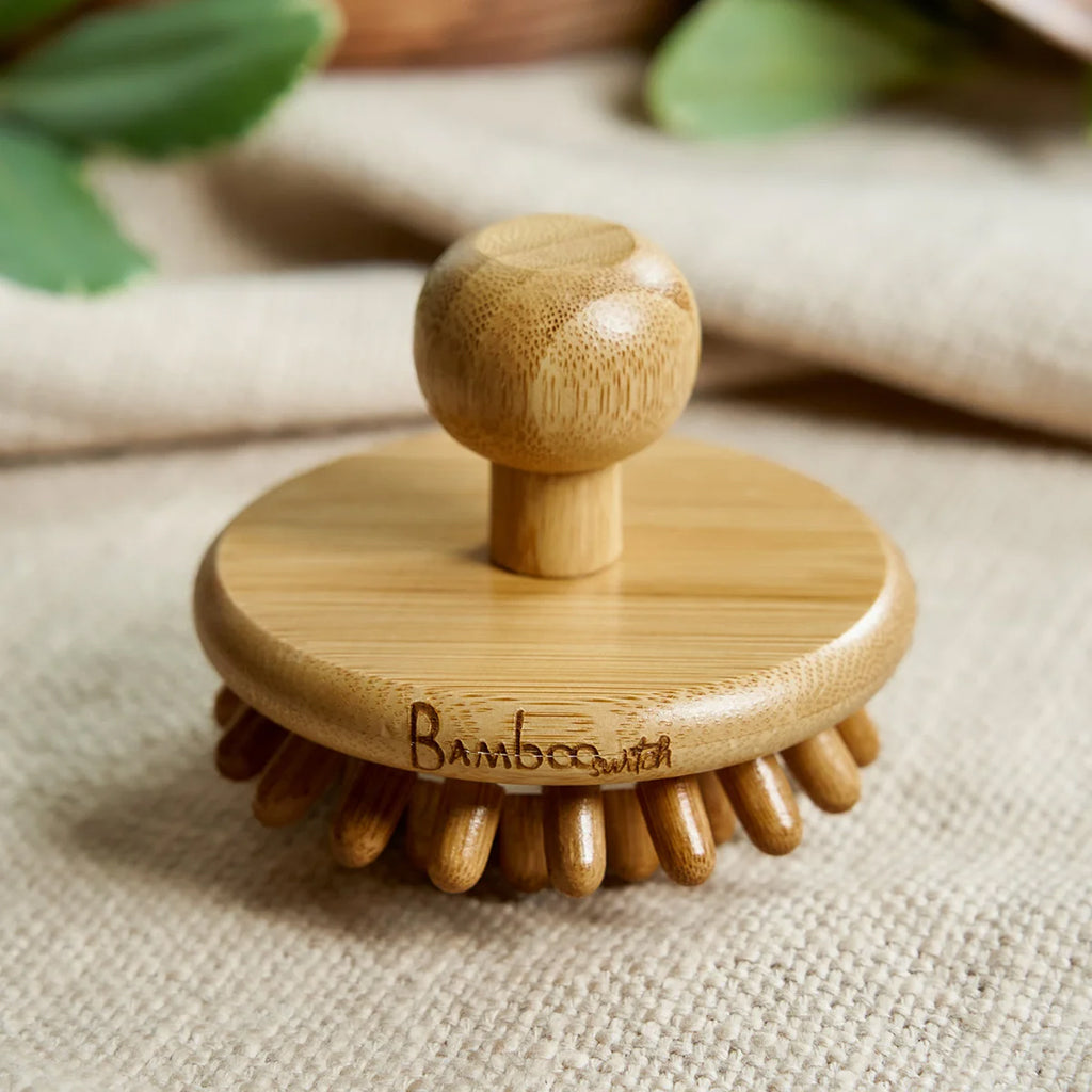Bamboo scalp massager with a handle on a textured fabric background