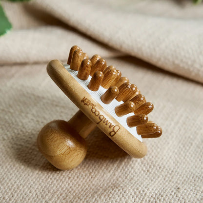 Bamboo Scalp Massager with textured surface on a beige fabric background