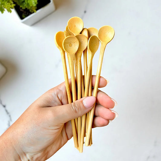 Hand holding a set of bamboo spoons over a kitchen surface