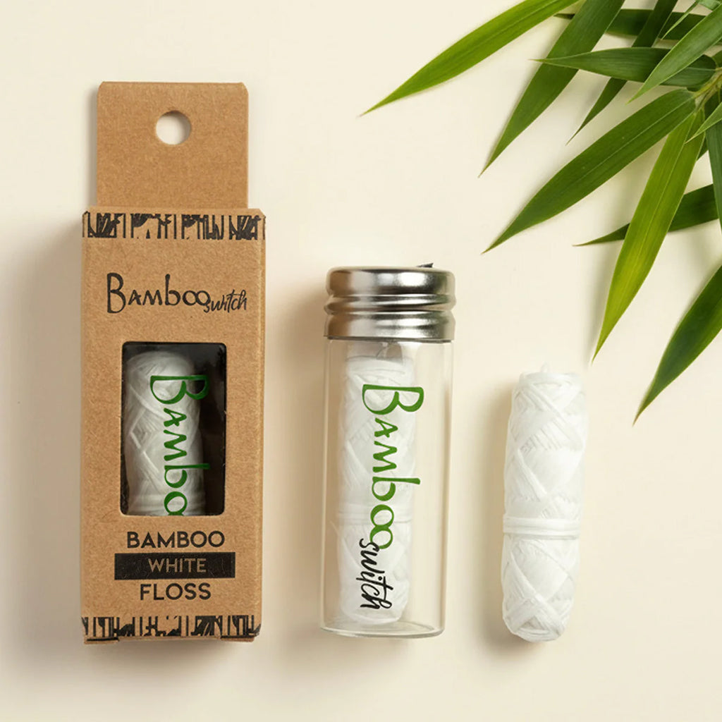 Bamboo switch white floss in packaging with a plant leaf on a beige background