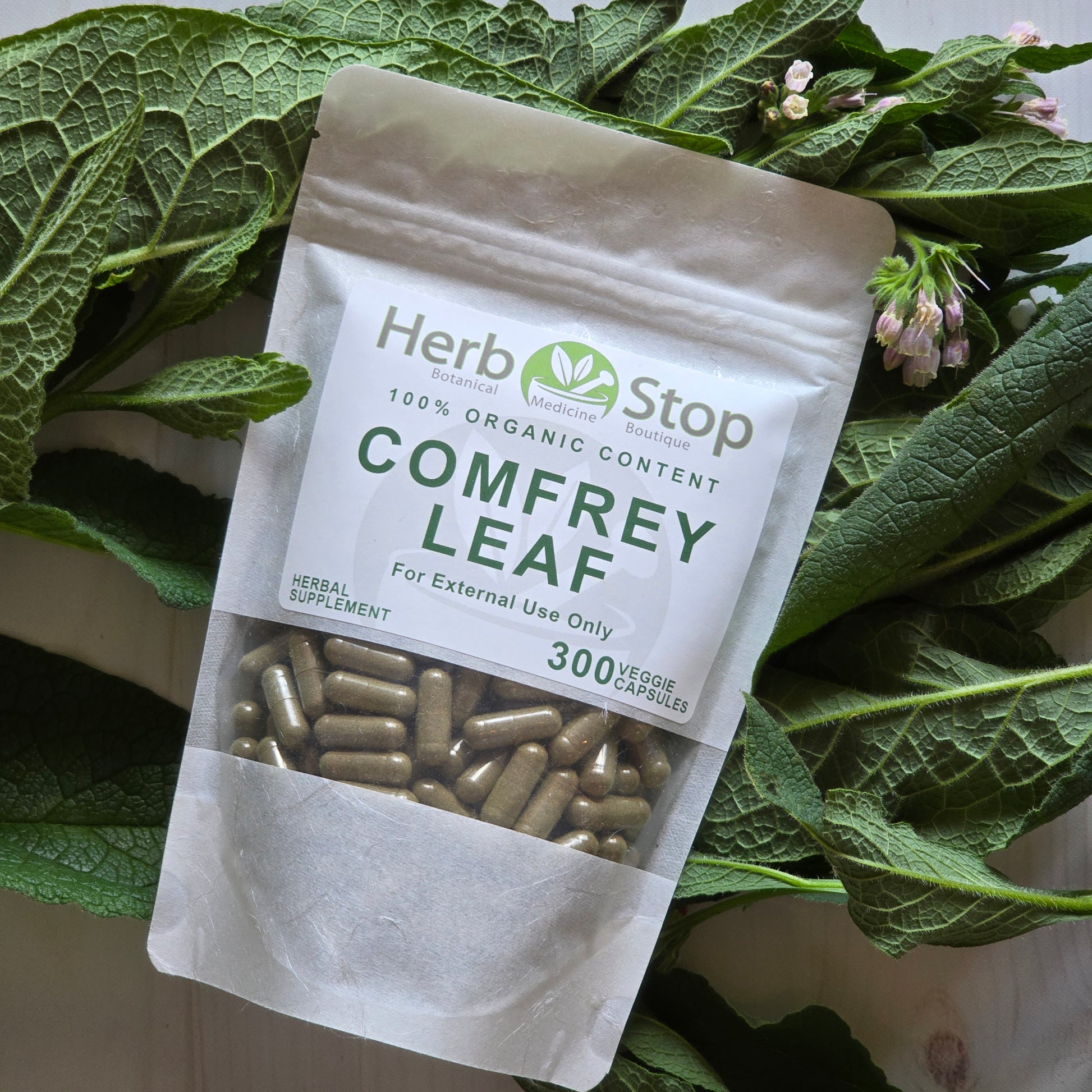Comfrey Leaf Capsules surrounded by comfrey leaves