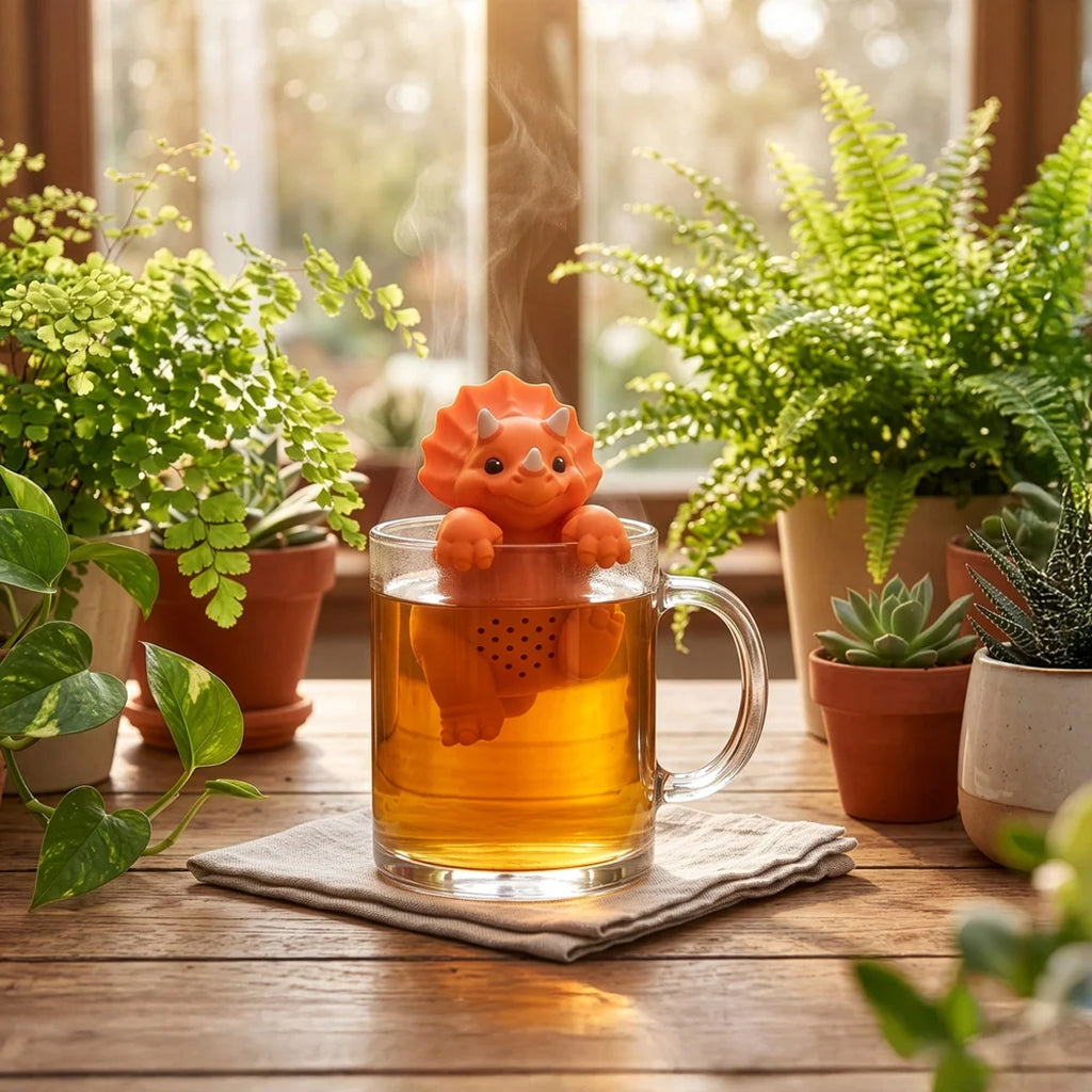 A clear glass mug filled with tea sits on a wooden table surrounded by potted green plants in a warm, sunlit indoor setting.